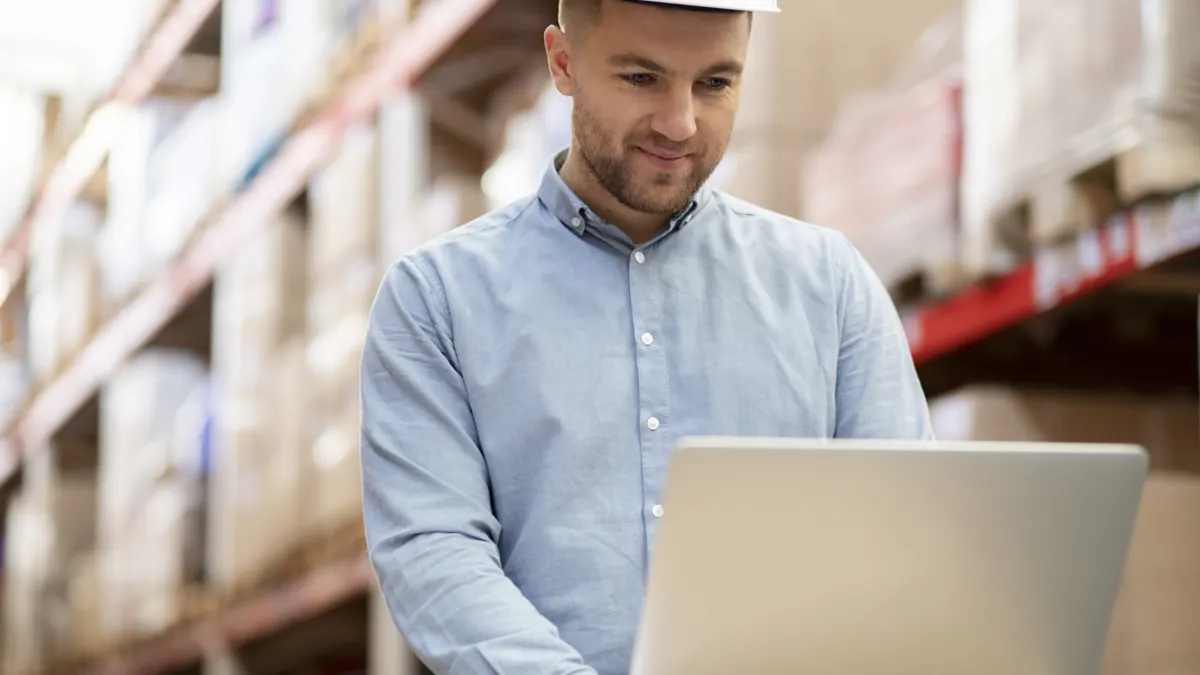Responsable de compras revisando una operación comercial en un portátil dentro de un almacén Responsable de compras revisando una operación comercial en un portátil dentro de un almacén