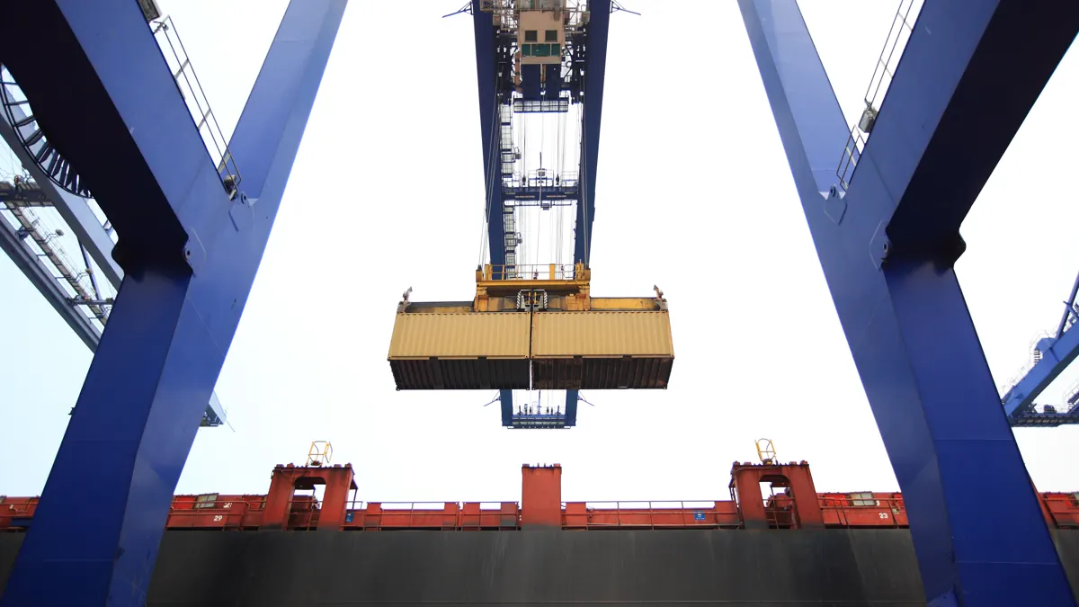Grúa portuaria elevando un contenedor sobre un buque de transporte marítimo